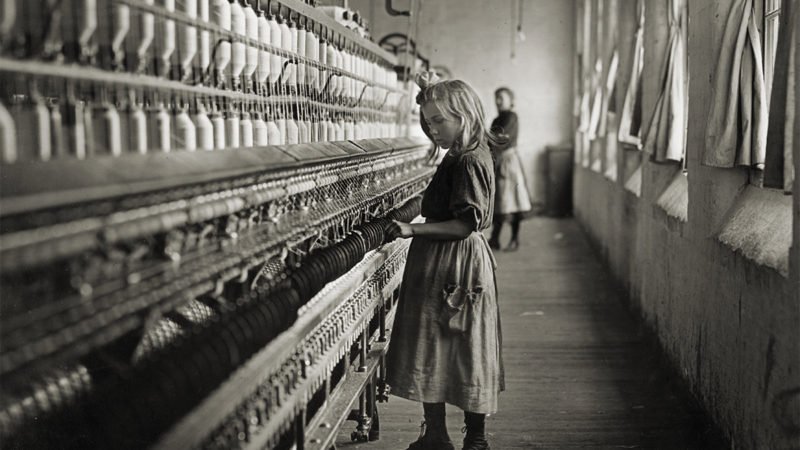 maedchen steht in einer fabrik und uebt kinderarbeit aus