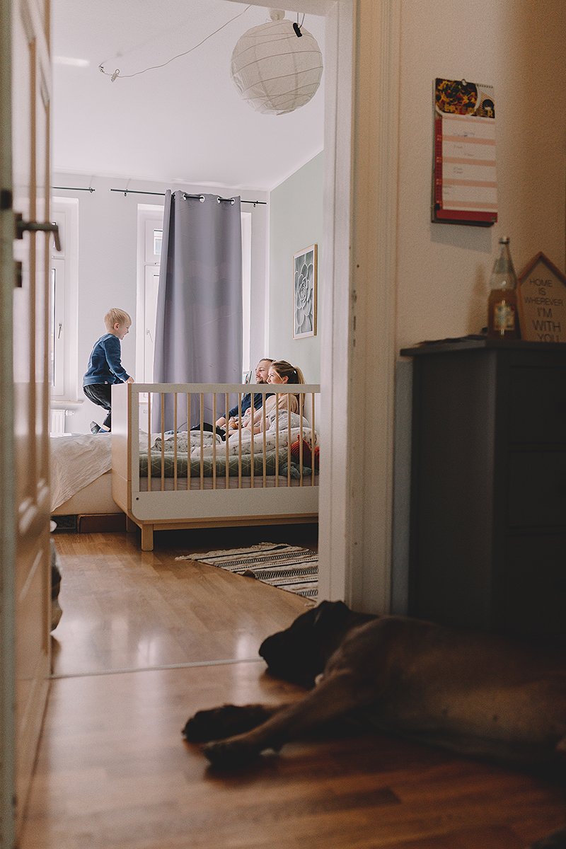 familienfotos aus dem schlafzimmer worin eltern mit kind lachend spielen