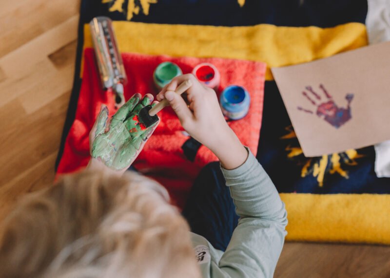 kind spielt mit malfarben an den haenden