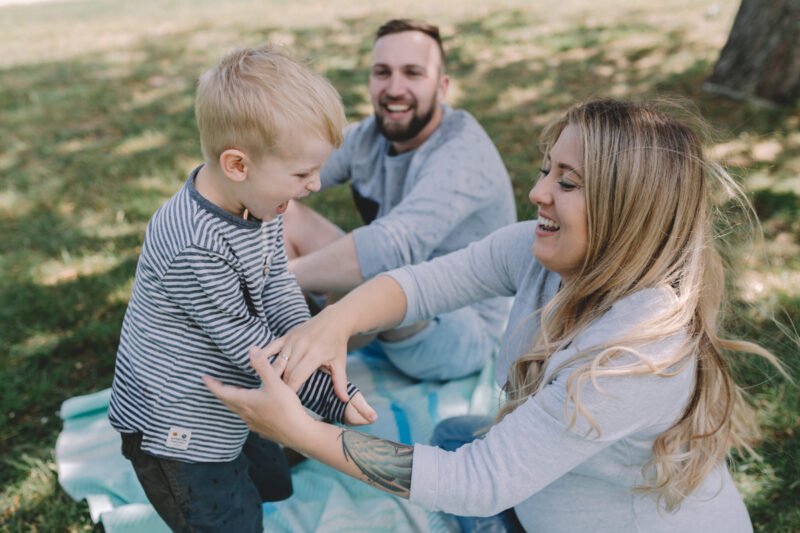 familienfotos draussen mit vater und mutter und kind lachend