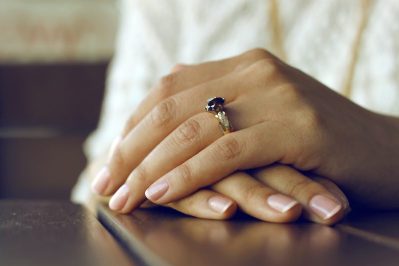 haende uebereinandergelegt auf dem tisch mit ring am finger