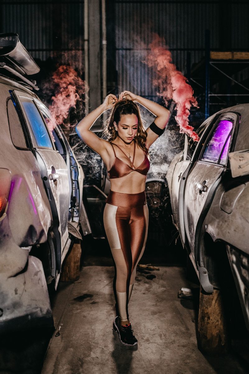 frau posiert zwischen zwei autos als fitness model