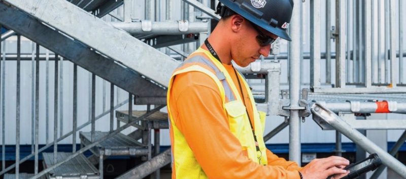 bauarbeiter ueberprueft ipad auf baustelle