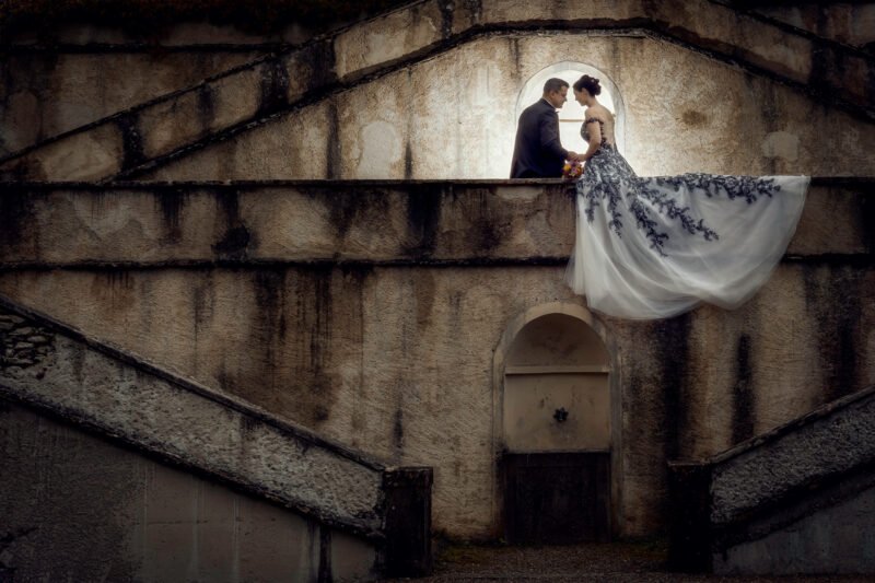 brautpaar sitzt auf mauer fuer hochzeitsfotos