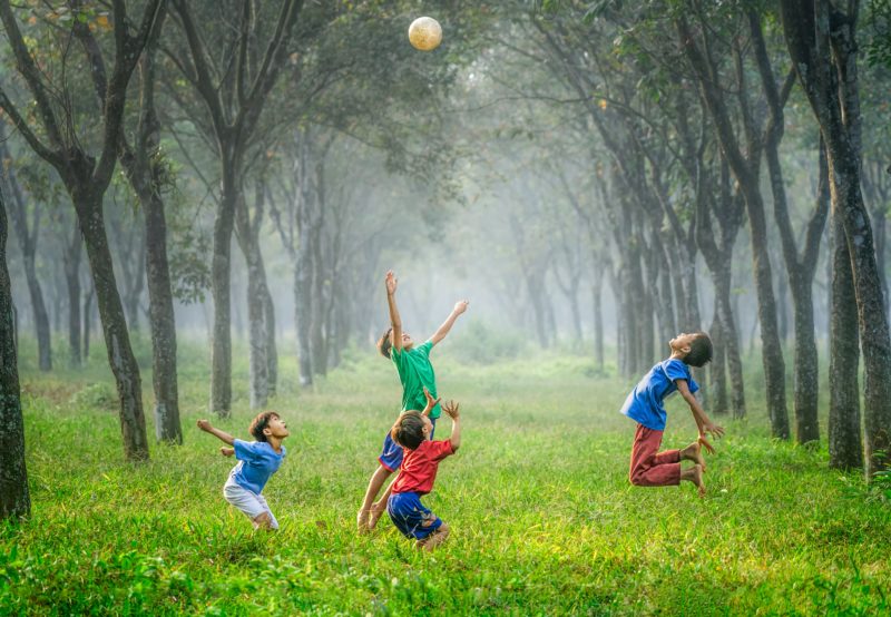 vier jungen spielen in einer allee fussball