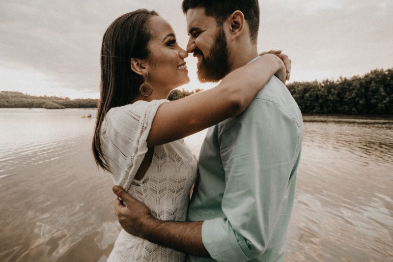 inszenierte fotografie eine frau und ein mann umarmen sich am wasser und lächeln sich an