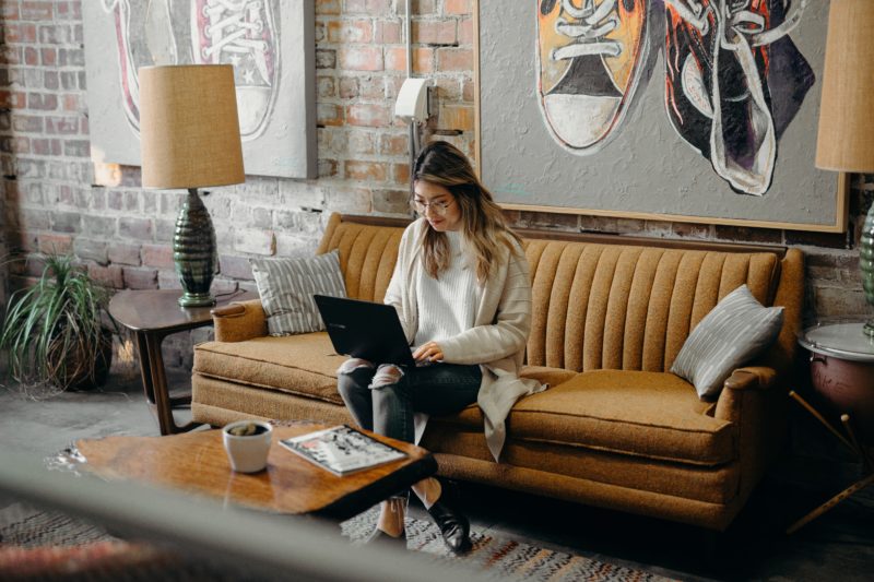 frau sitzt auf dem sofa vor ihrem laptop und posiert als katalog model