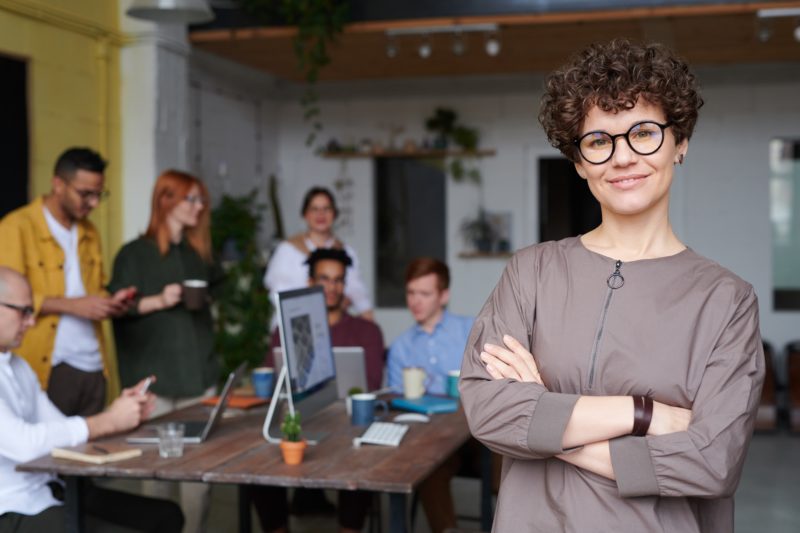 frau steht vor einem team mit verschraenkten armen