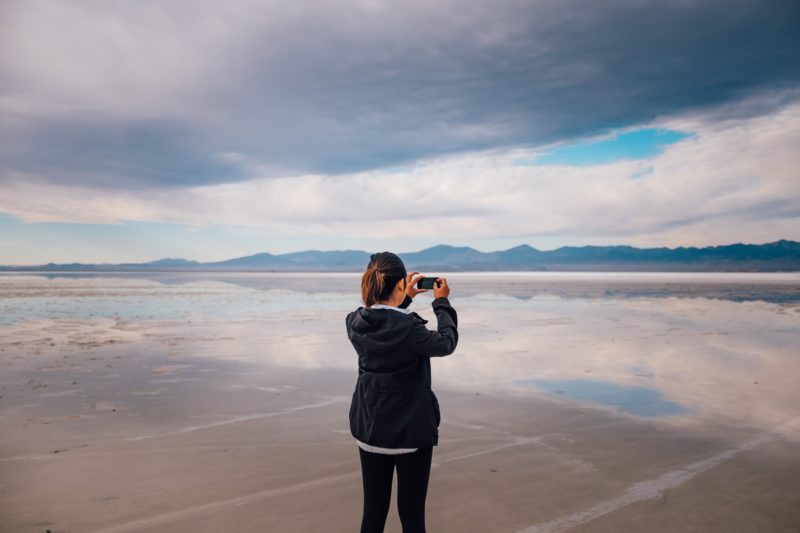 frau am strand mit mobiltelefon